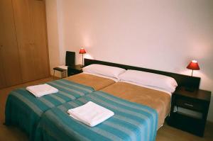 una camera da letto con un letto grande con due asciugamani sopra di Apartamentos Auhabitat Zaragoza, edificio de apartamentos turísticos a Saragozza