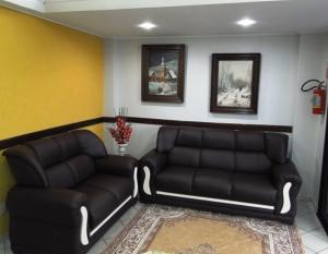 a living room with two leather couches and a rug at Paradise Hotel in Campo Grande