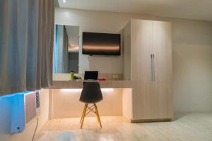 a room with a desk with a chair and a television at Kingsway Iligan Hotel in Iligan