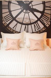 a white bed with two pillows in front of a clock at Fortress Apartments in Novi Sad