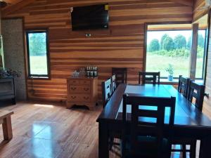 a dining room with a table and chairs and a television at Arriendo Diario de Cabaña en Villarrica in Voipire