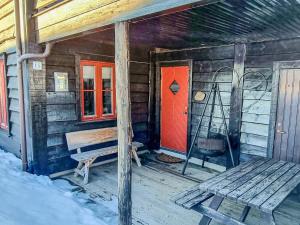 eine Holzhütte mit einer roten Tür und einer Bank in der Unterkunft 6 person holiday home in ÅSERAL-By Traum in Åseral
