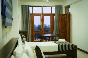 a room with a bed and a table and a window at Who Chance Hotel and Restaurant in Habaraduwa