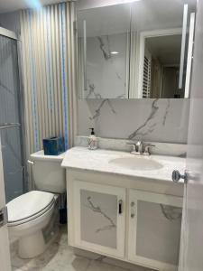 a bathroom with a sink and a toilet and a mirror at Penthouse in Miami to share in Miami