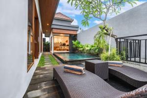 a backyard with a pool and chairs and a house at Villa Made Ubud in Ubud