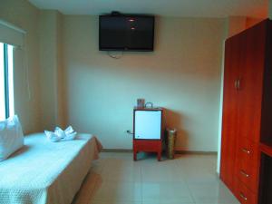1 dormitorio con cama, espejo y TV en Hotel Garzota Inn en Guayaquil