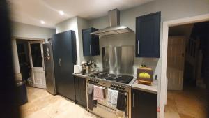 a kitchen with a stainless steel stove and blue cabinets at The Homestay in High Wycombe