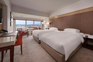 a large hotel room with two beds and a desk at Grand Hyatt Taipei in Taipei