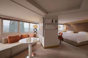 a hotel room with a bed and a couch and a table at Grand Hyatt Taipei in Taipei