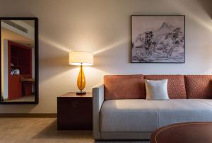 a living room with a couch and a mirror at Grand Hyatt Taipei in Taipei