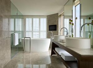 a bathroom with two sinks and two mirrors at Grand Hyatt Taipei in Taipei