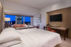 a hotel room with a large white bed and a desk at Grand Hyatt Taipei in Taipei