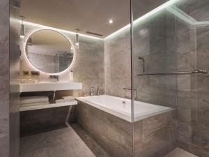 a bathroom with a tub and a sink and a mirror at Grand Hyatt Taipei in Taipei