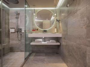 a bathroom with a shower and a sink and a mirror at Grand Hyatt Taipei in Taipei