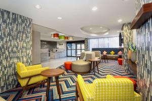 a lobby with yellow chairs and tables and a kitchen at Hampton Inn Orlando-International Airport in Orlando