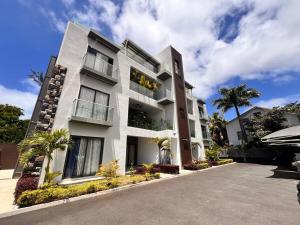 a large white building with palm trees in front of it at Coastal View 2 Apartments North in Grand Baie
