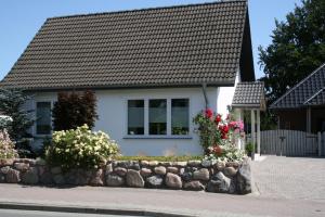 a small white house with a stone wall at Frey - Ferienhaus über zwei Etagen mit Terrasse in Eggebek