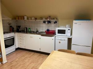 a small kitchen with white appliances and a table at Sjökaptensgården Bed & Breakfast in Åsljunga