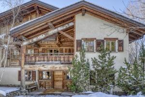 a log home with a large front door in the snow at Chalet Sapin in Megève