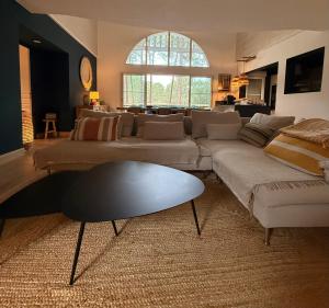 ein Wohnzimmer mit Sofa und Tisch in der Unterkunft Villa 10pers avec piscine privée in Lacanau