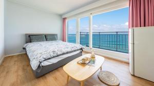 ein Schlafzimmer mit einem Bett, einem Tisch und einem großen Fenster in der Unterkunft Gangneung Haerang Pension in Gangneung