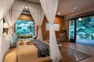 a bedroom with a bed with curtains and a large window at Pramana Giri Kusuma in Payangan +75 photos