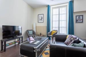 a living room with a couch and a tv at Remy - Appt 68 m2 cosy - Place de Jaude & tramway in Clermont-Ferrand
