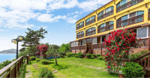 a yellow building with red flowers in front of it at Ganghwa hana & alice spa pension in Incheon