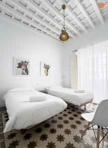 two beds in a room with white walls at Casa Trajano Grupo AC Gestion in Cádiz +11 photos