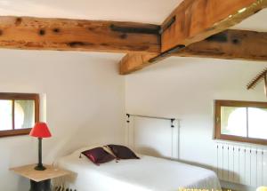 ein Schlafzimmer mit einem Bett, einer Lampe und zwei Fenstern in der Unterkunft Maison spacieuse à Saint-André-de-Valborgne avec jardin 120 m² in Saint-André-de-Valborgne