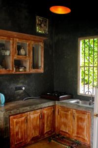 马特勒Hide Surf Hostel Madiha的厨房配有木质橱柜、水槽和窗户