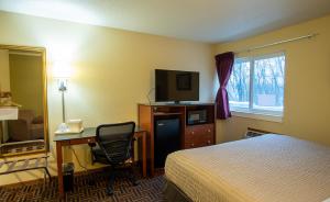 a hotel room with a bed and a desk and a television at Coratel Inn and Suites By Jasper River Falls in River Falls