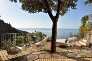 a patio with two chairs and a table and a tree at Hotel Piccolo Sant'Andrea in Praiano