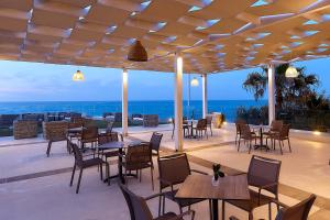 a patio with tables and chairs and the ocean at St Constantin Sea Hotel & Spa Resort in Gouves