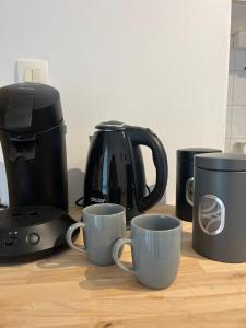 eine Kaffeemaschine und drei Kaffeetassen auf dem Tisch in der Unterkunft Charming T1 - Parking - Metro St Agne in Toulouse + 8 Fotos