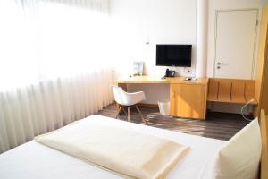 a room with a bed and a desk with a television at Cristall Hotel in Waghäusel