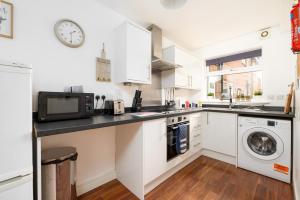 a white kitchen with a microwave and a washer and dryer at Ideal 2 Bedroom Ground floor Apartment By Jesswood Properties for Contractors & Business, Free Parking and Wifi in Hinckley