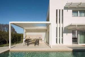 a white house with a table and chairs and a swimming pool at Villa Georgiana in Funtana