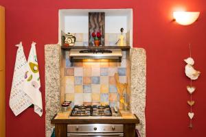 アローナにあるCasa Corte Alla Roccaの赤い壁のキッチン(コンロ付)