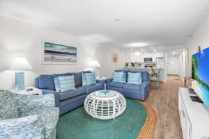 sala de estar con sofás azules y TV en Pelicans Roost 106 condo, en Sanibel