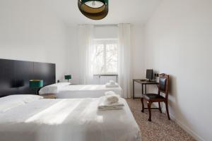 a white bedroom with two beds and a chair at GuestHost - Comfy Family Apartment in Milan in Milan