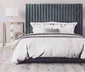um quarto com uma cama branca e uma cabeceira verde em Pine rooms and suites em Ruiru