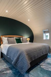 a bedroom with a large bed with a green wall at Unique 1 Bedroom Eco-Retreat in Old Chalford! in Enstone