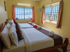 two beds in a bedroom with two windows at Kodai Hillscape in Kodaikānāl +256 photos
