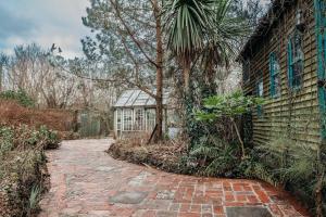 a brick walkway leading to a greenhouse in a garden at Heron's Perch- A pond-side retreat with cinema room in Callington