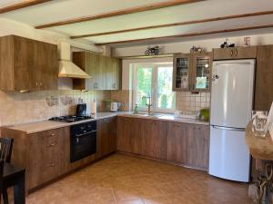 a kitchen with wooden cabinets and a white refrigerator at Domek w Las Bagnas in Konopki Małe