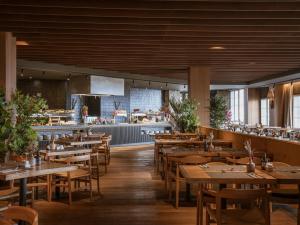 a restaurant with wooden tables and chairs and a kitchen at The Mountains Hotel in Sierra Nevada
