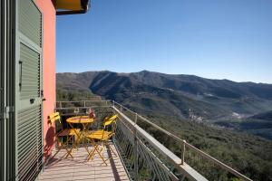 a balcony with a table and chairs and mountains at Il nido tra gli ulivi in Lucinasco