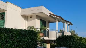 Casa blanca con balcón y matorrales en Casa Vacanza GLI ULIVI, en Santa Cesarea Terme