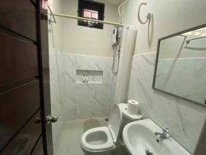 a white bathroom with a toilet and a sink at JMorino Pension House in Puerto Princesa City